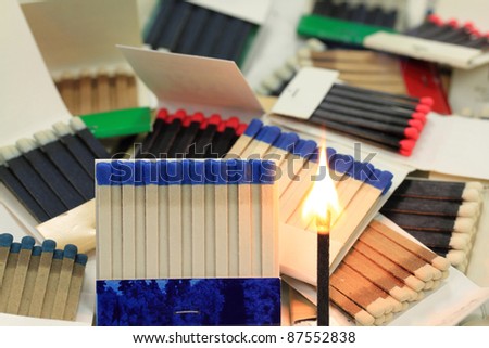 Group of different models, styles, sizes and colours Matchbooks (Book of Matches) and fired Paper Stick with flame. Focal point is only front match book and fired paper stick.