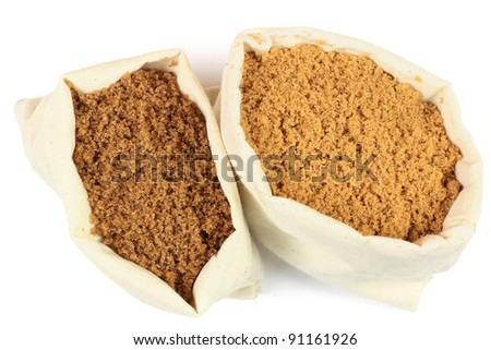 Two bags from white fabric full with different types brown sugar over white background, light brown natural classic Brown Sugar and darker Brown crunchy texture Brown Sugar with special flavor.