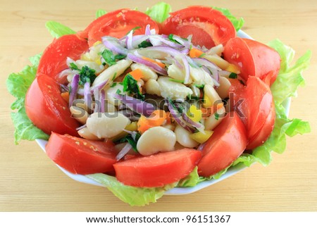 Salad from Boiled Huge Lima Beans mixed with Seasonings and dressed with Olive Oil, Balsamic Vinegar, Key Lime Juice, served in Porcelain Bowl over Lettuce Leaves and decorated with Tomatoes.