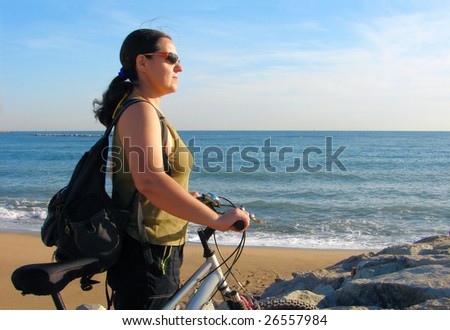 young woman tourist with a bicycle and a backpack on seacoast