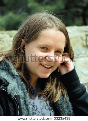 girl  teenager listens to music and talks by a mobile phone to ear-phones