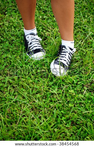 feet of the child of the teenager in gym shoes on a grass