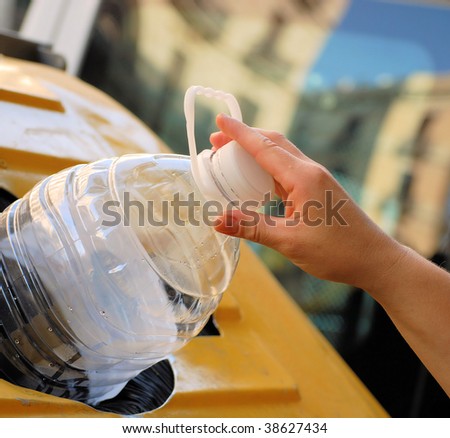 female hand throwing out a plastic large bottle in container for processing and recycling