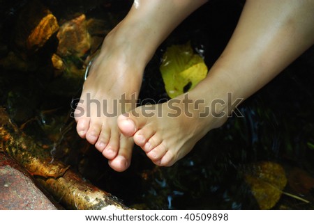 tired female feet in water of the mountain river