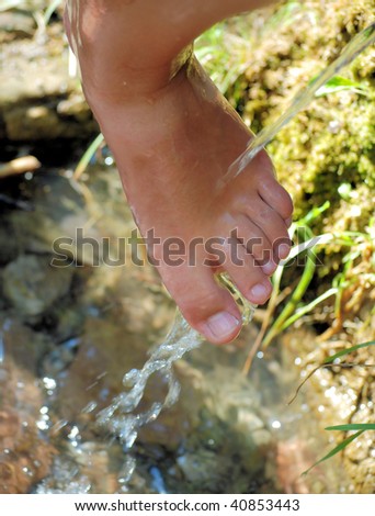 female foot under a stream of water of a natural natural source