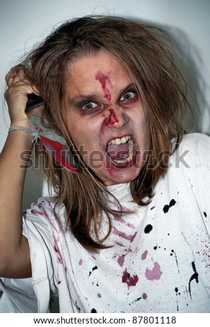 girl of the zombie in anger and fury with a blood-stained knife on a holiday halloween