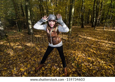 Crazy young woman makes fun in the forest by autumn.