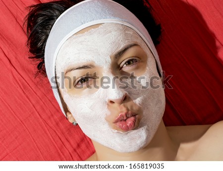 Positive young woman with white smoothing face mask sending kiss.