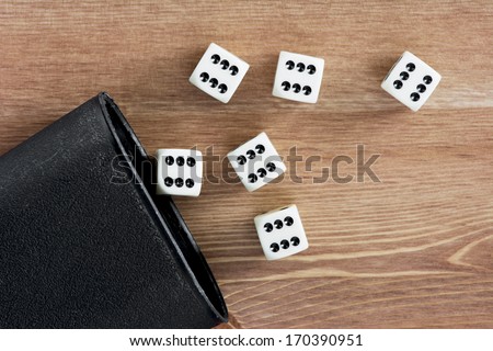 Dices with cup on the wooden table.