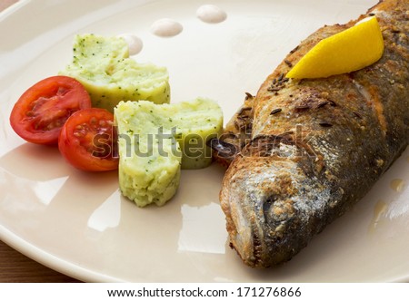 Grilled trout with two hearts of mashed potatoes and cherry tomatoes.