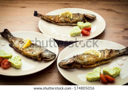 Delicious grilled fish with hearts of mashed potatoes, lemon and cherry tomatoes.