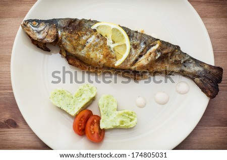 Delicious grilled fish with two hearts of mashed potatoes and cherry tomatoes.
