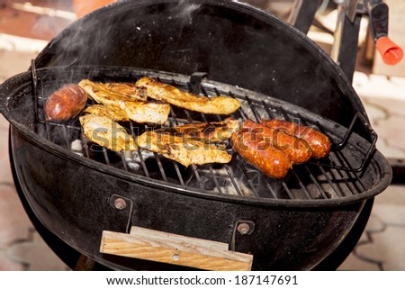 Sausages and chicken meat on a grill. Garden party.