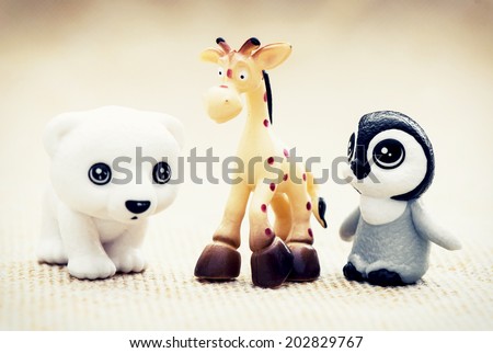 Three plastic toy figurines. Penguin, giraffe and white teddy bear.