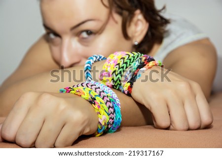 Young caucasian brunette with colorful rubber bracelets on her hands. Beauty and fashion.