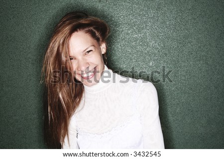 Laughing girl wearing white shirt standing near green wall