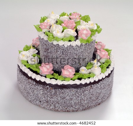 Beautiful multi-tiered wedding cake with white frosting. The cake is 		decorated with purple roses.