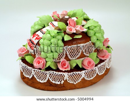 Cake with white frosting, cake is decorated with purple roses, grape.
