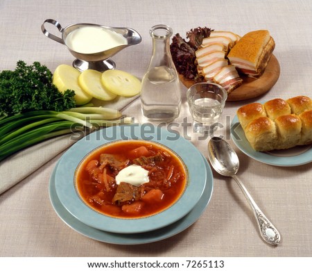 A meal of Russian borsch soup with cream, buns, roasted pork, cheese slices and vegetables.
