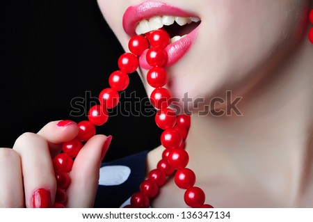 Woman with open mouth, makeup and white teeth beating red chaplet. Photo of the part of the face