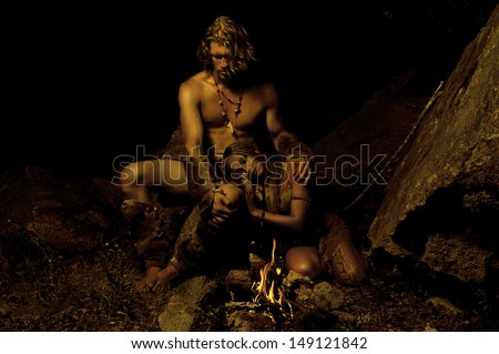 Primitive Man And His Woman Sitting Near The Fire In The Cave