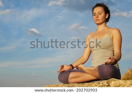 girl sitting in the lotus position on the stone in the warm sunlight.
