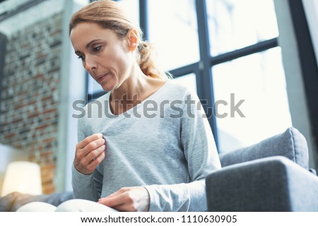 Gradual process. Beautiful mature woman touching sweater and having hot flash