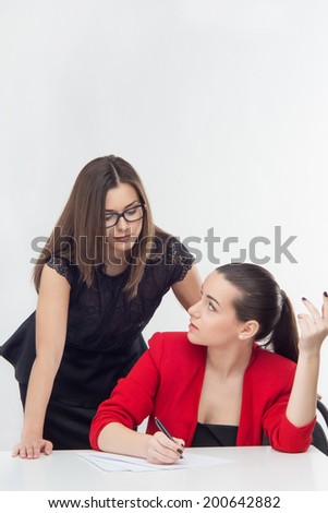 Beautiful manageress sitting and writing the proposed offers from her assistant. Isolated on white background