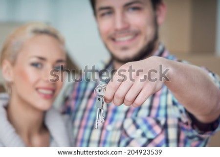 Selected focus on keys of the new house. Smiling happy couple on background