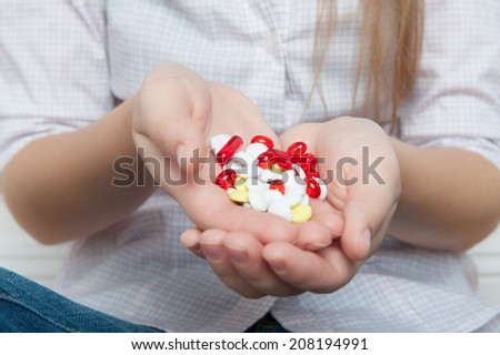 Heap of colorful pills lying on the palms of girl wearing nice blouse