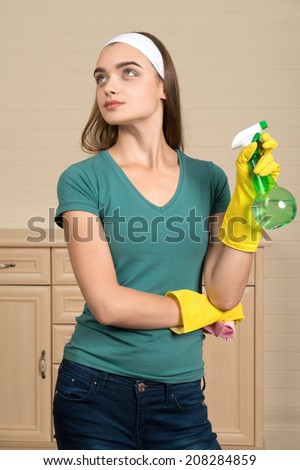Half-length portrait of nice dark-haired housemaid wearing white fillet and holding water sprayer in one hand thinking about one more flat where she must clean