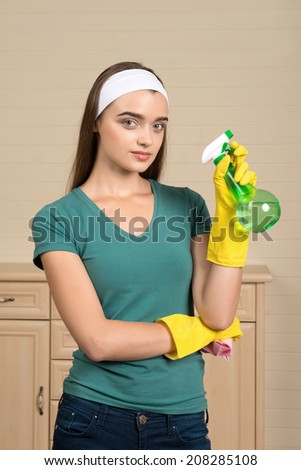 Half-length portrait of nice dark-haired housemaid wearing white fillet and holding water sprayer in one hand thinking about one more flat where she must clean