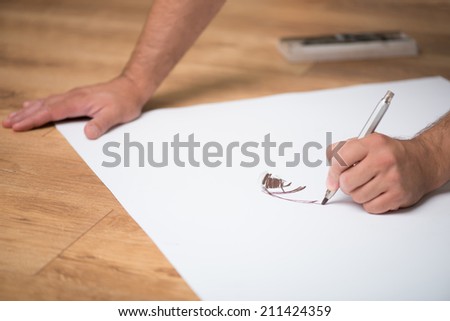 Painter drawing on the whatman with the lead pencil on the floor
