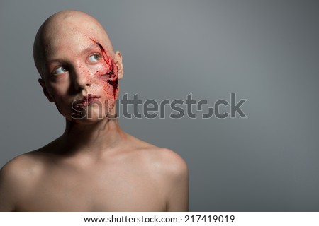 Half-length portrait of naked woman getting into the accident having a big terrible gash on her face isolated on grey background