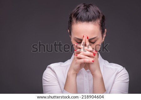 Half-length portrait of dark-haired beautiful woman wearing white blouse having a nice manicure thinking hard about something. Isolated on dark background