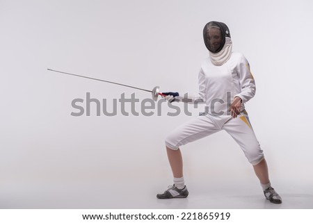 Full-length portrait of nice young woman wearing fencing costume and mask practicing before very important competitions. Isolated on white background