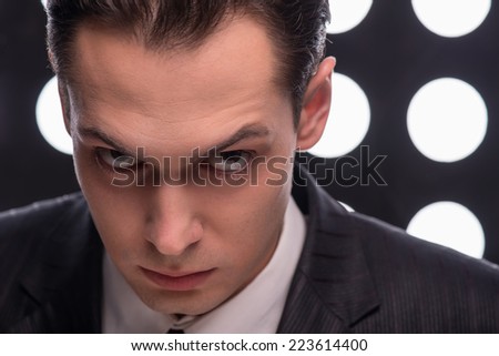 Half- length portrait of young handsome serious man looking at us with suspicion