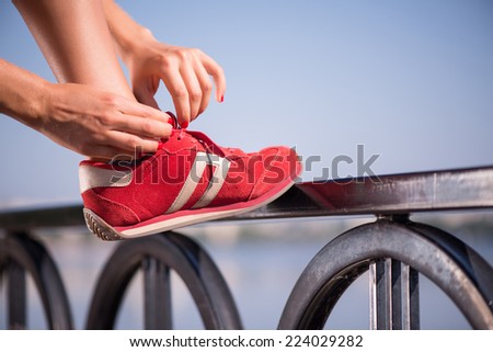 Selective focus on the legs of the woman wearing red jogging shoes putting right at it