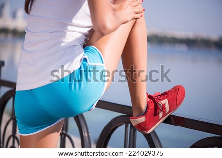 Selective focus on the young sexy woman wearing white T-shirt and blue shorts standing back loosening up near the river