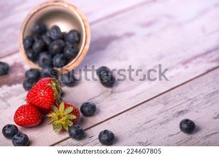 Selective focus on the red tempting strawberries lying on the table near the heap of delicious blackberries on background. Top view