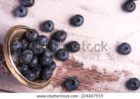 Selective focus on the copper top with little blackberries in it lying on the wooden table. Top view