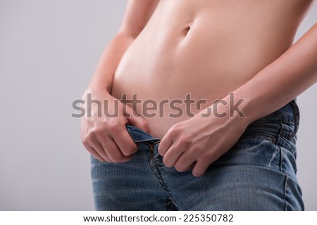 Half-length portrait of sexy beautiful blonde with great figure wearing only jeans showing us her great body. Isolated on white background