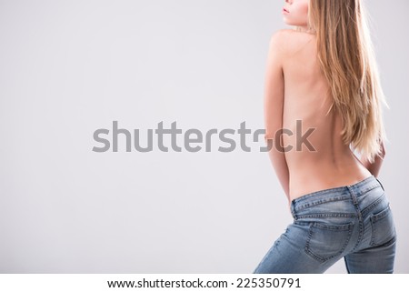 Half-length portrait of sexy beautiful blonde with great figure wearing jeans standing back showing us her great body. Isolated on white background