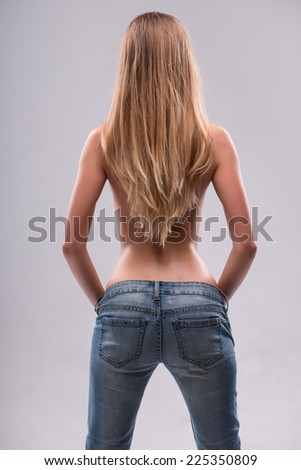 Half-length portrait of sexy beautiful blonde with great figure wearing jeans standing back showing us her great body. Isolated on white background