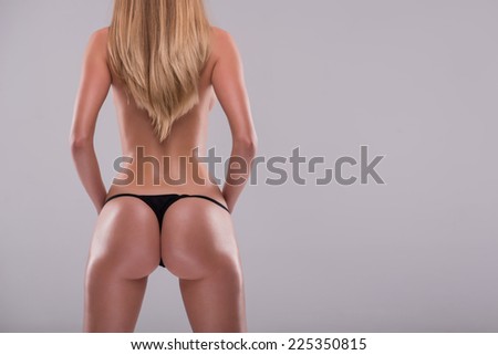 Half-length portrait of sexy beautiful blonde with great figure wearing black lingerie standing back showing the beauty of her wonderful body. Isolated on white background