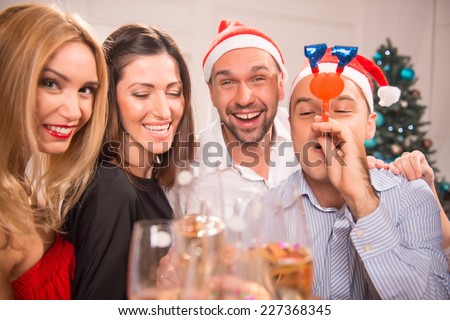 Half-length portrait of the company of happy young smiling friends standing together drinking the champagne greeting each other with the New Year and having fun