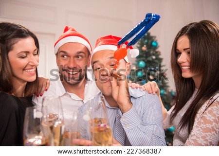 Half-length portrait of the company of happy young smiling friends standing together drinking the champagne greeting each other with the New Year and having fun