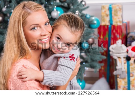Selective focus on smiling beautiful mom and daughter sitting together hugging each other waiting their presents