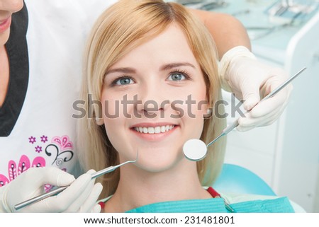 Half-length portrait of young fair-haired lovely smiling girl sitting on the dentist chair satisfied with the end of treatment looking at us
