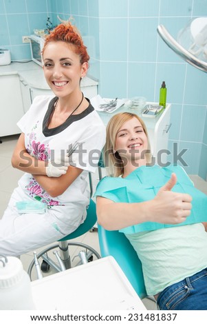 Half-length portrait of young fair-haired lovely smiling girl sitting together with the dentist showing that there is nothing better than healthy teeth